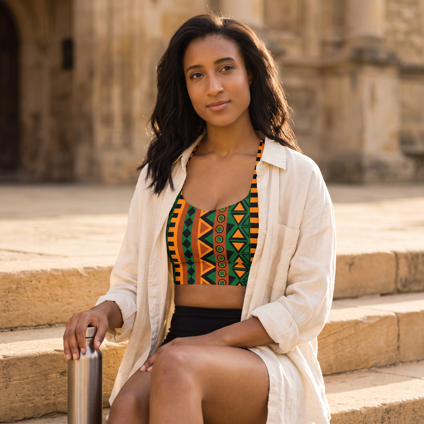 Woman on stone steps wearing the longline sports bra under an open linen shirt