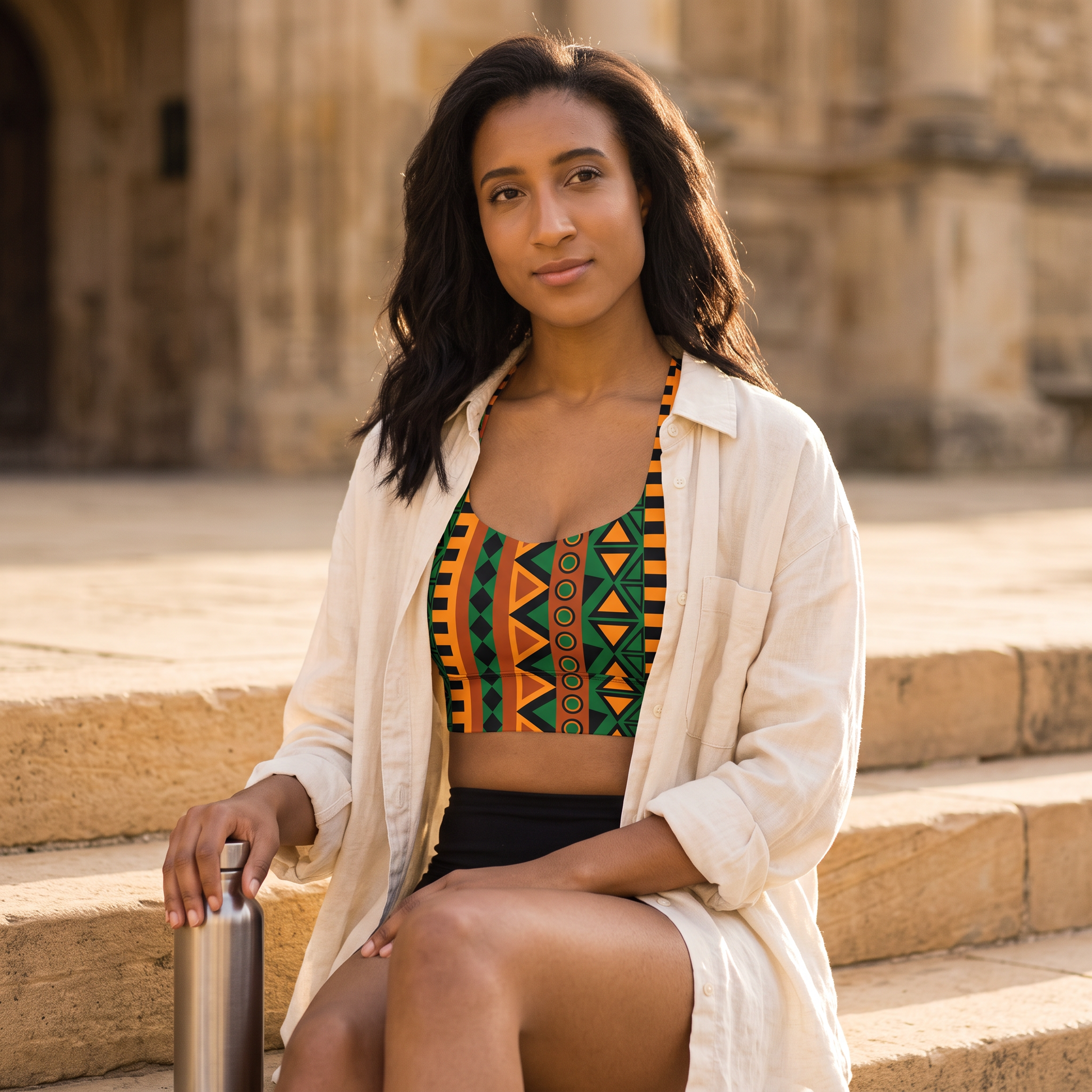 Woman on stone steps wearing the longline sports bra under an open linen shirt